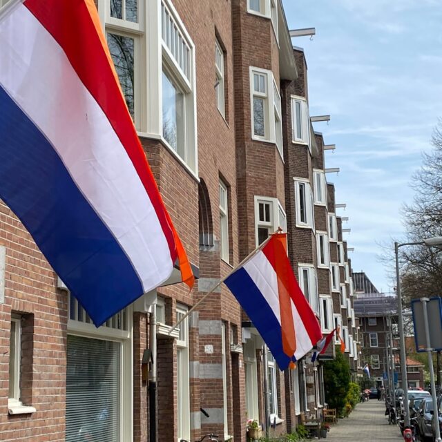 Photo by Anthony Tilke A row of brick buildings with flags hanging from the windows